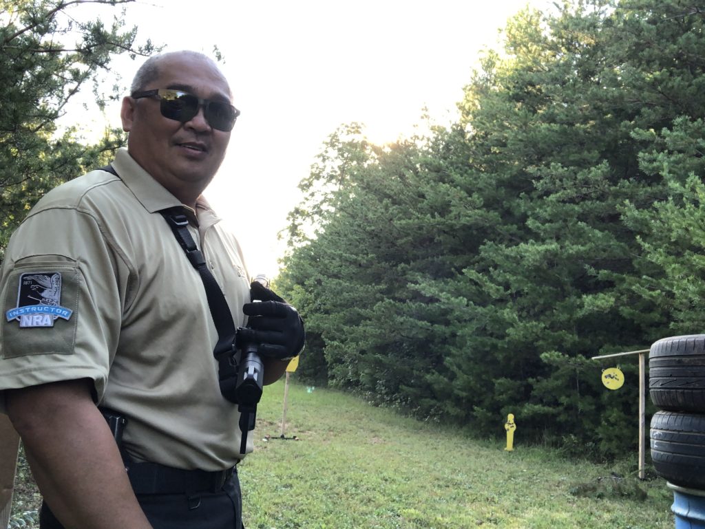 A Filipino man (Pat Dimaano) stands to the side in a khaki-colored shirt with a backdrop of trees.